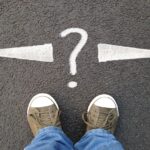 feet standing on asphalt with arrows pointing left and right with question mark